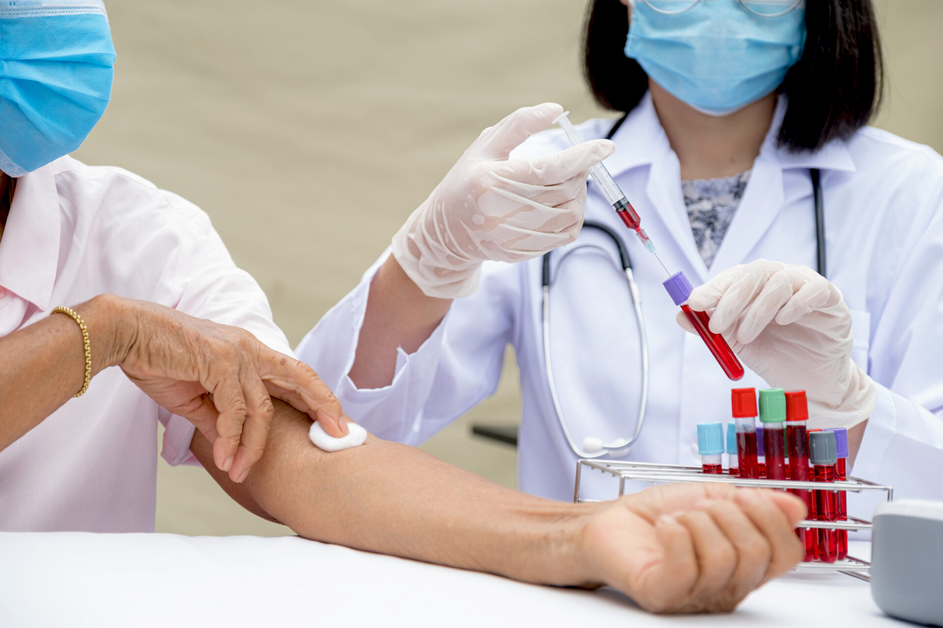 A doctor hands with a syringe and a sample of blood tube for analysis and test virus disease in the laboratory from elderly patients, This research is plasma biomedicine for diagnostic medical healthcare.