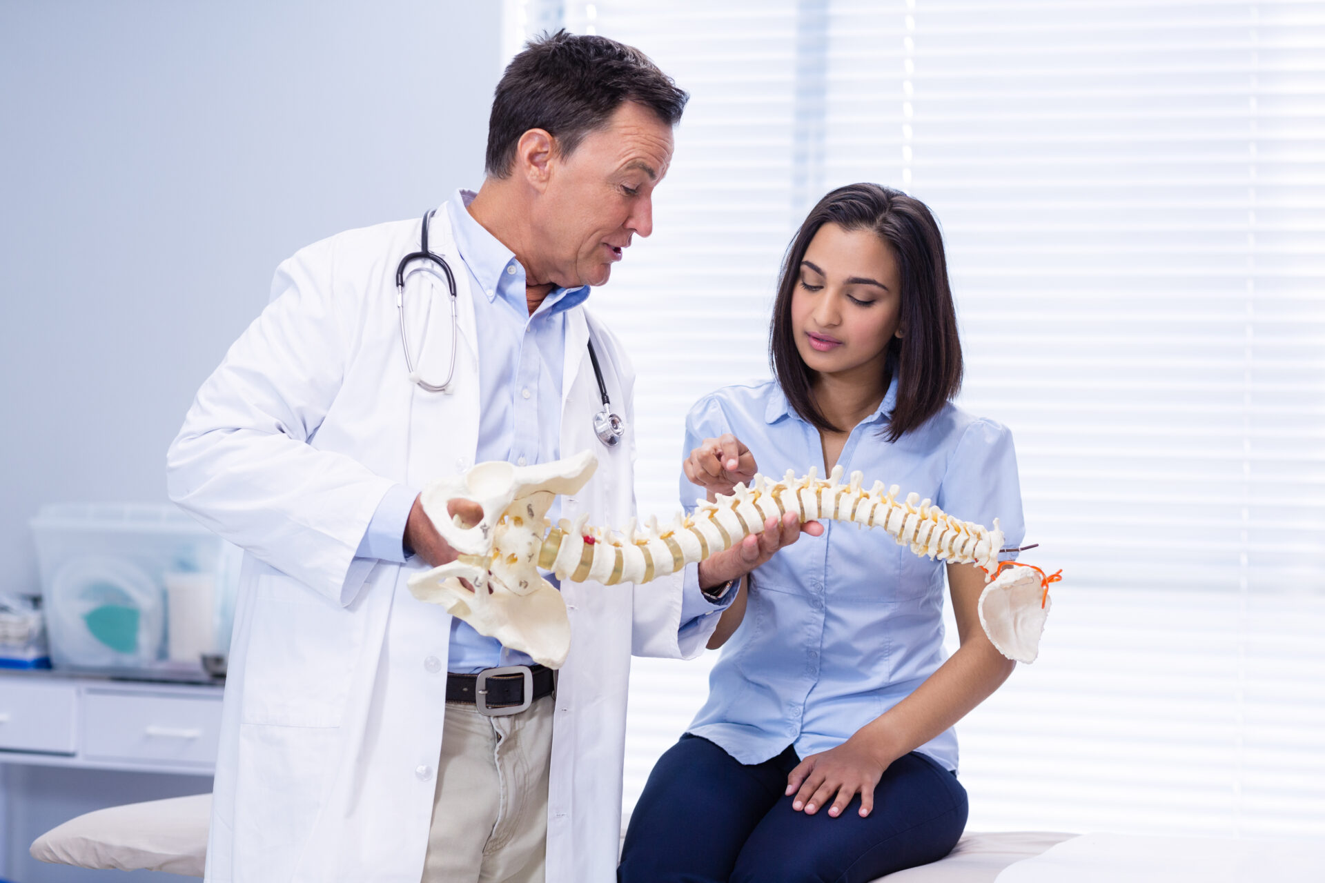 Physiotherapist explaining spine model to patient in clinic